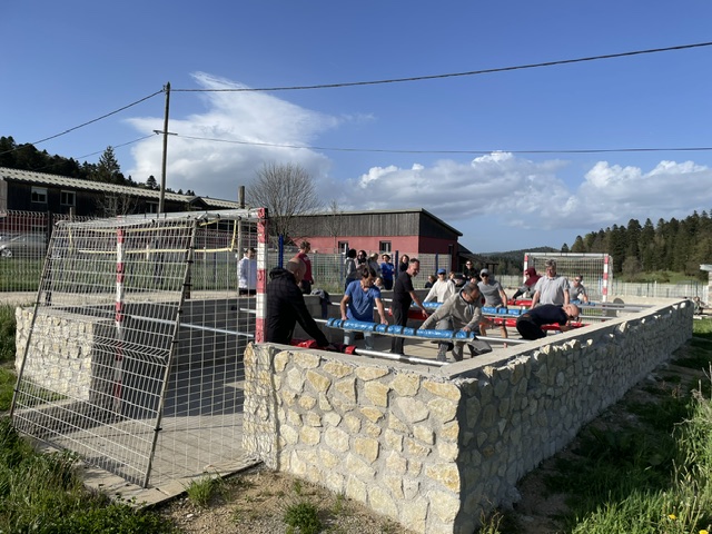 Groupe en pleine partie de baby-foot humain sur le terrain du gîte